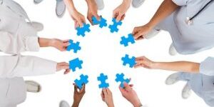 Directly above shot of medical team holding blue jigsaw pieces in huddle against white background